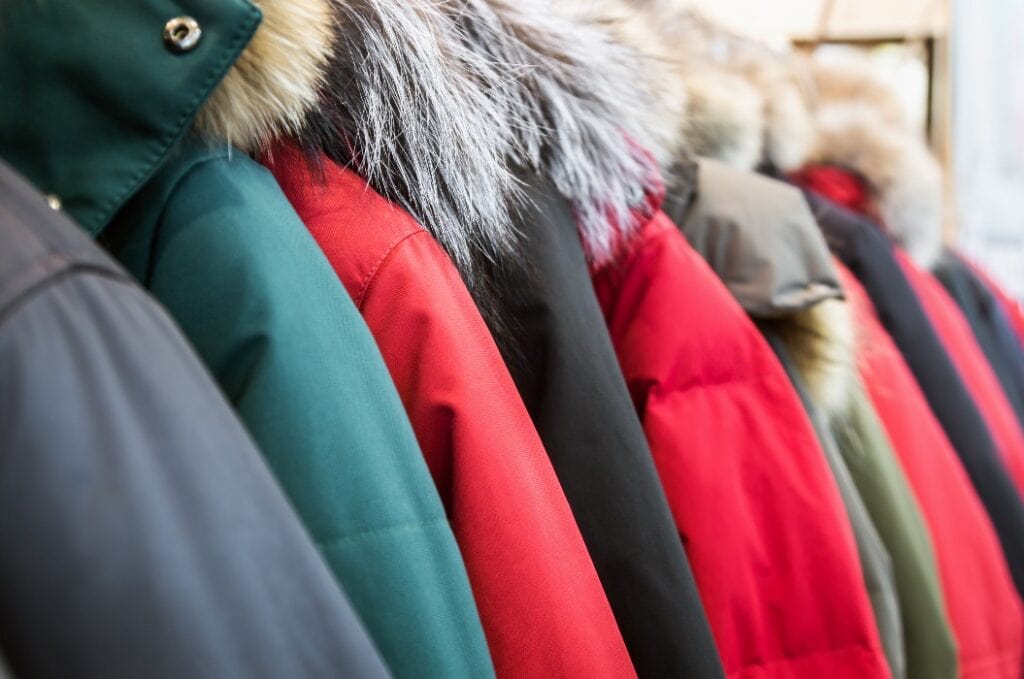 assortment of winter jackets and down jackets on store hangers.